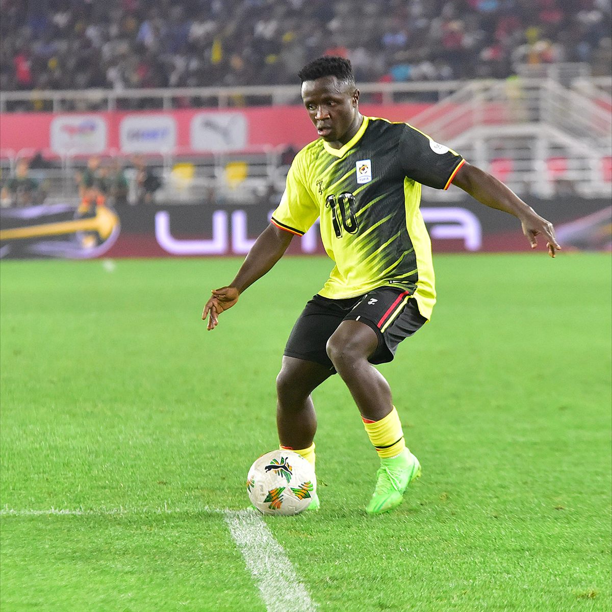 Futbolista de Uganda conduce la pelota ante Argelia